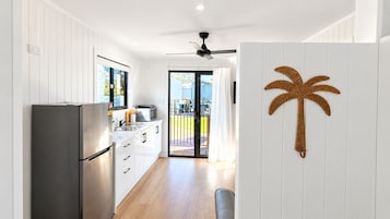 Una cocina moderna con un refrigerador de acero inoxidable, armarios blancos y un amplio ventanal.