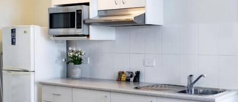 Una cocina moderna con armarios blancos, microondas, estufa y lavaplatos.