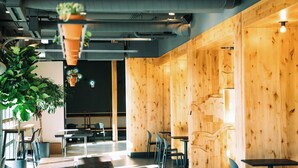 A modern interior with wooden walls, hanging plants, and a seating area with tables and chairs. - Colorado Springs City Core Urban Stay with 2 Queen Beds (Colorado Springs)
