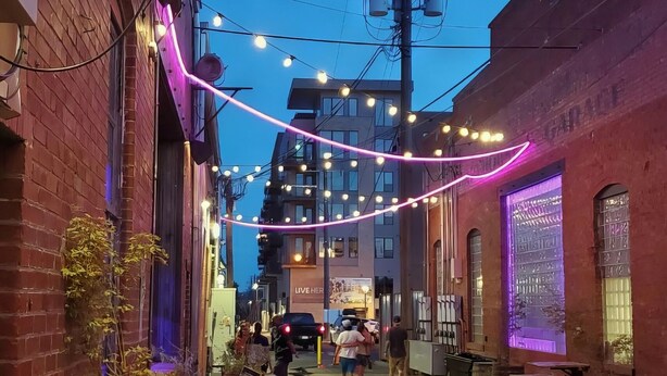 A narrow street with outdoor seating, string lights, and buildings with brick facades. - Colorado Springs City Core Urban Stay with 2 Queen Beds (Colorado Springs)