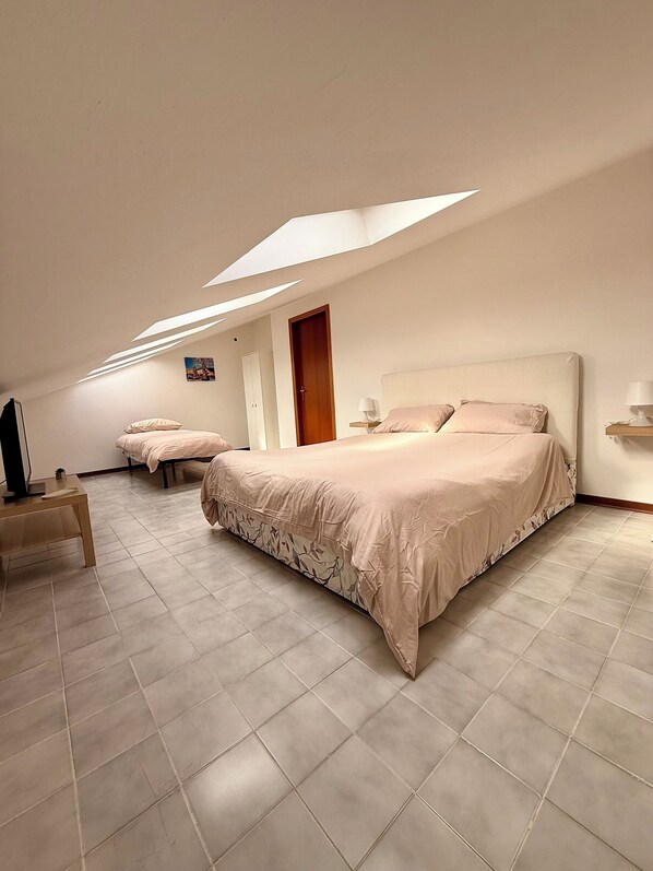 A bedroom with a large bed, a desk, and a wardrobe.