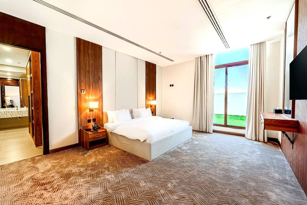 Un cuarto de hotel con una cama grande, televisión, escritorio y vista al exterior.