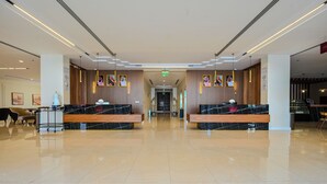 En rymlig entréhall med marmordiskar i receptionen, ett välstädat golv och inramade tavlor på väggarna.