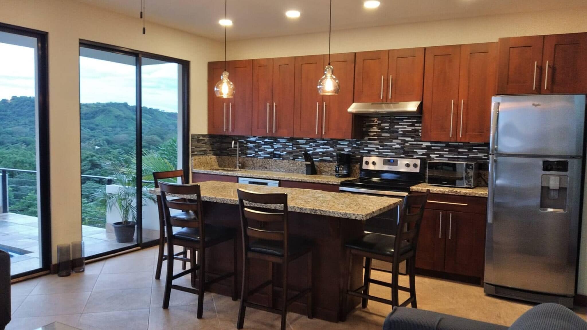 A modern kitchen with a large island, stainless steel appliances, and wooden cabinets.