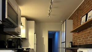 Een moderne keuken met witte kasten, een ingebouwde oven en een wand bekleed met baksteen.