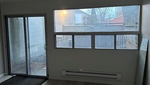 Een kamer met een groot raam, een schuifpui en een ingebouwde airconditioning.