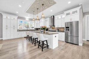 A modern kitchen with white cabinetry, a central island with bar stools, stainless steel appliances, and pendant lighting. - 🦩Book Me Baby! Sea Breeze Escape in Santa Rosa Beach🦩 (Santa Rosa Beach)