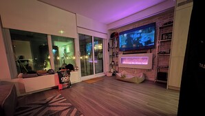 Ein modernes Wohnzimmer mit großem Fernseher, Kamin und gemütlicher Sitzecke.