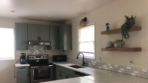 A kitchen with grey cabinets, a white marble countertop, a built-in oven, a microwave, and a window with blinds. - Cozy Home: Fire Pit+Pets: near Riverside+Downtown (Jacksonville)