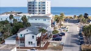 A coastal hotel with a parking lot, a stop sign, and a view of the ocean.