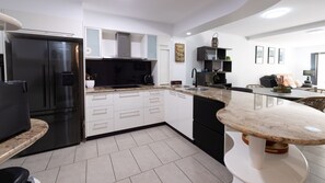 A modern kitchen with a built-in refrigerator, a microwave, and a coffee maker. - Waterline Poolside Apartment (Agnes Water)