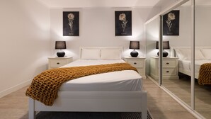 Una camera da letto moderna con un letto, comodini, uno specchio e opere d'arte alle pareti.
