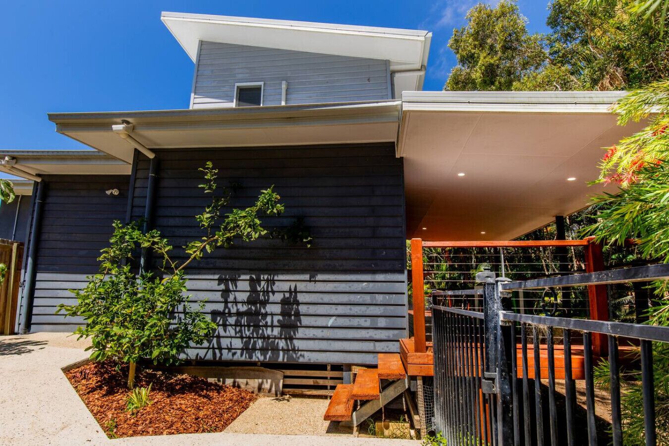 A modern house with a dark facade, a small window, and a covered porch.