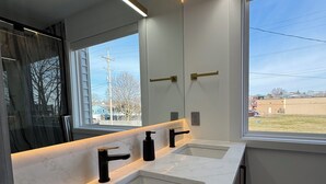 Un baño moderno con dos lavamanos, un espejo grande y vistas al exterior.