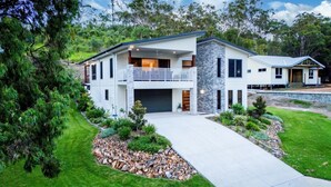 A two-story house with a balcony, a driveway, and a well-maintained lawn. - Coastal Haven - Agnes Water (Agnes Water)