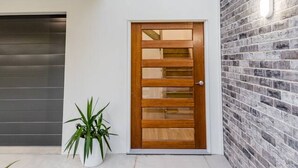 A modern building with a two-story structure, a wooden door, and a brick wall. - Coastal Haven - Agnes Water (Agnes Water)
