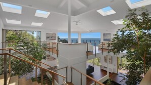 En modern inredning med flera våningsplan, stora fönster och utsikt över havet.