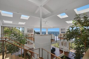Ein modernes Interieur mit mehreren Ebenen, großen Fenstern und Blick auf das Meer.