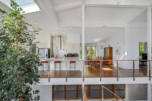 Eine geräumige, moderne Küche mit hohen Decken, einem Essbereich mit Holzmöbeln und einer Treppe, die zu einer oberen Ebene führt.