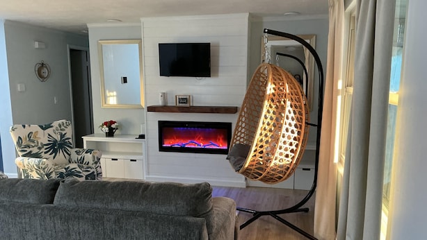 A living room with a fireplace, a television, a hanging chair, and a sofa. - Nomad Hub: Ideal for Long Stays - Pet friendly (Cranberry Township)