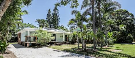 A two-story house with a covered porch, surrounded by a variety of trees and a well-maintained lawn.