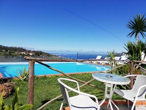 Ein Poolbereich mit Blick auf das Meer, einem Tisch mit Stühlen und einem Zaun.