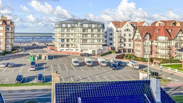 Una zona residenziale costiera con edifici a più piani, un parcheggio e vista sul mare.