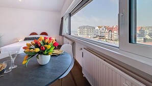 Una camera d'albergo con un letto, un tavolo da pranzo con un vaso di fiori e un'ampia finestra vista città.