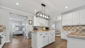 A spacious kitchen with white cabinetry, a central island, and a hanging light fixture. - Luxurious Farm Stay Near Houston  -  5BR Gated Acreage (Waller)