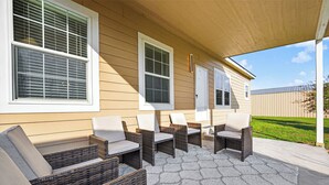 A covered patio with wicker furniture and a patterned rug. - Luxurious Farm Stay Near Houston  -  5BR Gated Acreage (Waller)