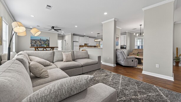 A modern living room with a sectional sofa, a dining area, and a kitchen in the background. - Luxurious Farm Stay Near Houston  -  5BR Gated Acreage (Waller)