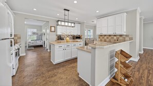 A modern kitchen with white cabinetry, a central island, and a built-in microwave. - Luxurious Farm Stay Near Houston  -  5BR Gated Acreage (Waller)