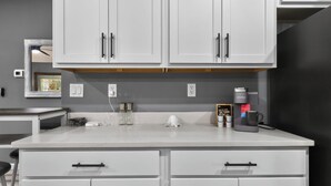A kitchen with white cabinets, a coffee maker, and a kettle on the counter. - Welcome Home! 2-bedroom house in lovely St. Augustine with cool AC (St. Augustine)
