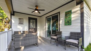 A covered porch with wicker furniture, a ceiling fan, and two signs on the wall. - Welcome Home! 2-bedroom house in lovely St. Augustine with cool AC (St. Augustine)