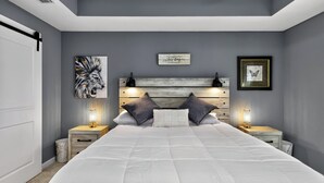 A bedroom with a large bed, two bedside tables, a headboard, and wall art. - Welcome Home! 2-bedroom house in lovely St. Augustine with cool AC (St. Augustine)