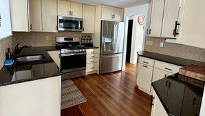 Una cocina moderna con armarios blancos, electrodomésticos de acero inoxidable y piso de madera.
