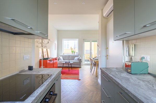 A modern kitchen with a central island, a dining area with a sofa and table, and a view to the outside. - Spacious bright and cozy penthouse with terrace close to metro station (Roma)