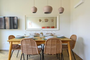 A dining area with a wooden table set for six, wicker chairs, and pendant lighting. - Spacious bright and cozy penthouse with terrace close to metro station (Roma)