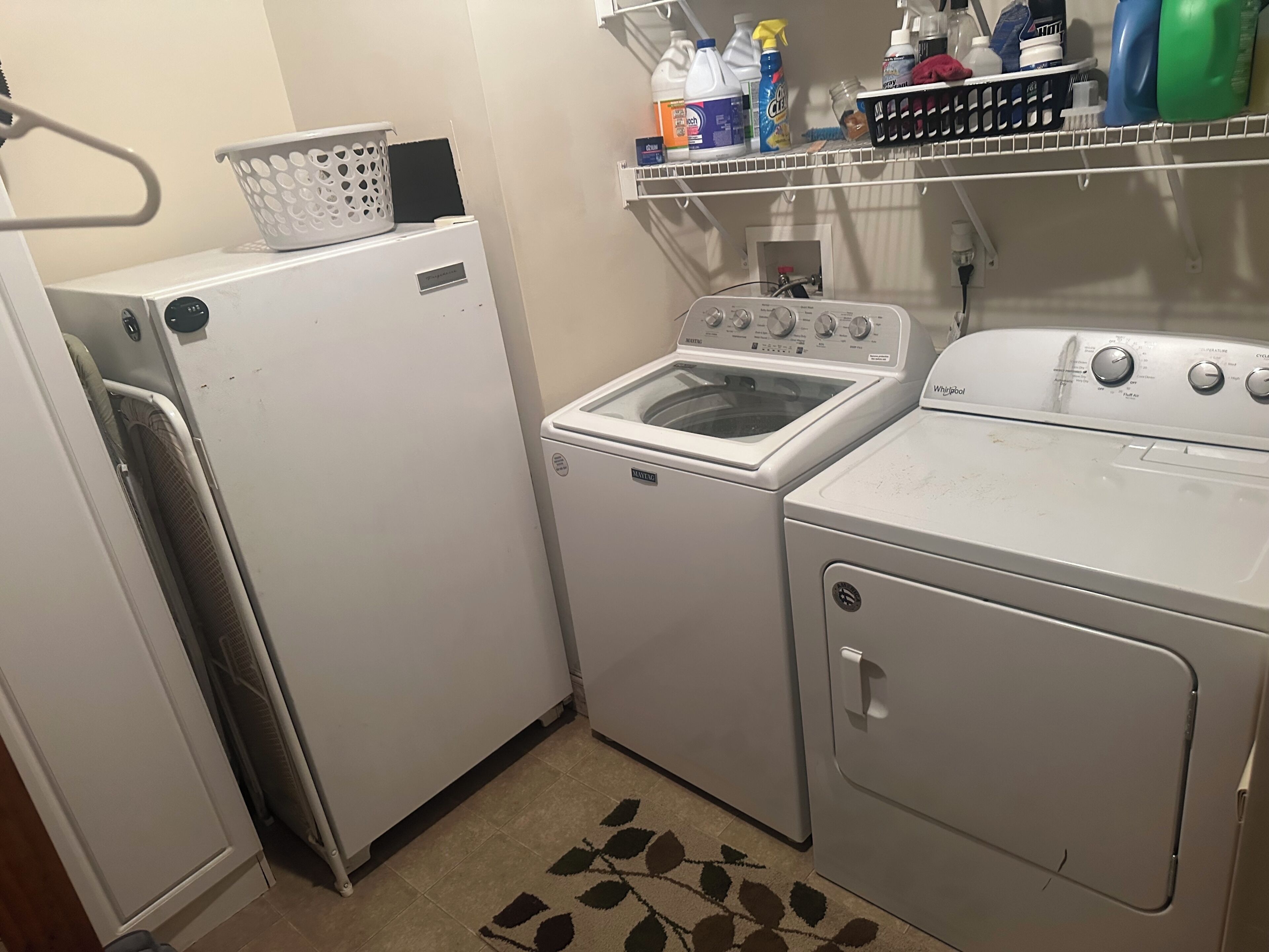 Une buanderie équipée d’un lave-linge, d’un sèche-linge et d’étagères où sont rangés les produits de nettoyage.