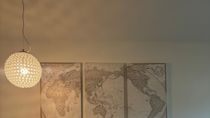 A blue sofa with patterned cushions, a globe map on the wall, and a hanging light fixture.