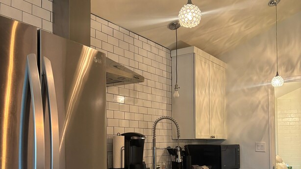A modern kitchen with stainless steel appliances, white cabinetry, and pendant lighting.
