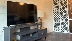 A modern living room with a flat-screen TV, a decorative lamp, and a patterned partition.