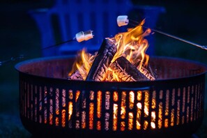 Un feu de camp avec des bûches et des guimauves grillées.