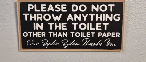 A sign with a humorous message about not throwing anything in the toilet except toilet paper.