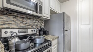 Keittiössä on Frigidaire-merkkinen liesi, mikroaaltouuni, jääkaappi ja laatoitettu seinäosa liesen takana.