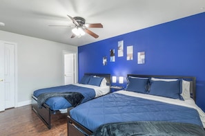 A hotel room with two beds, a ceiling fan, and a blue accent wall. - Stadium View Balcony | Walk to AT&T + Globe Life! (Arlington)