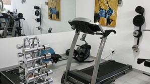 Un gimnasio con cinta de correr, un soporte para pesas y equipo de ejercicio.