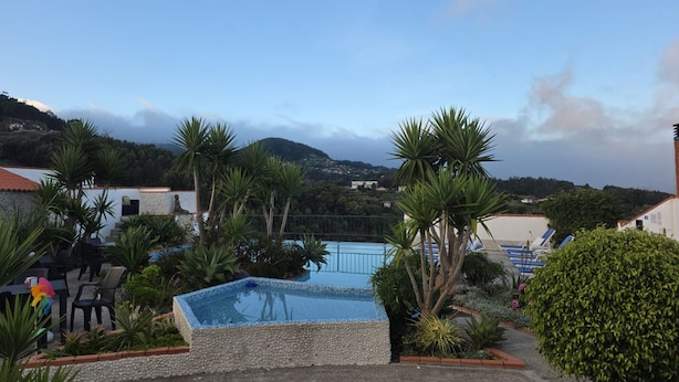 Piscina cercada por palmeiras e uma paisagem montanhosa.