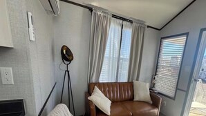A living room with a brown leather sofa, a beige armchair, a glass coffee table, and a floor lamp.