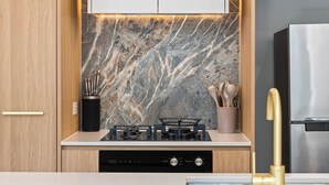 Une cuisine moderne dotée d’une cuisinière à gaz, d’appareils électroménagers en acier inoxydable et d’un dosseret en marbre.